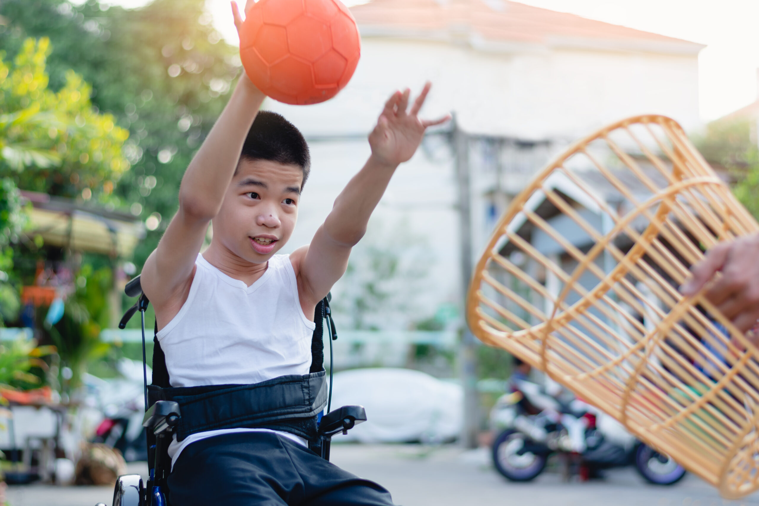 Asian special child on wheelchair is playing chair ball to strengthen muscles in the house, Lifestyle of disabled child,Life in the education age of children,Happy disability kid stay at home concept.